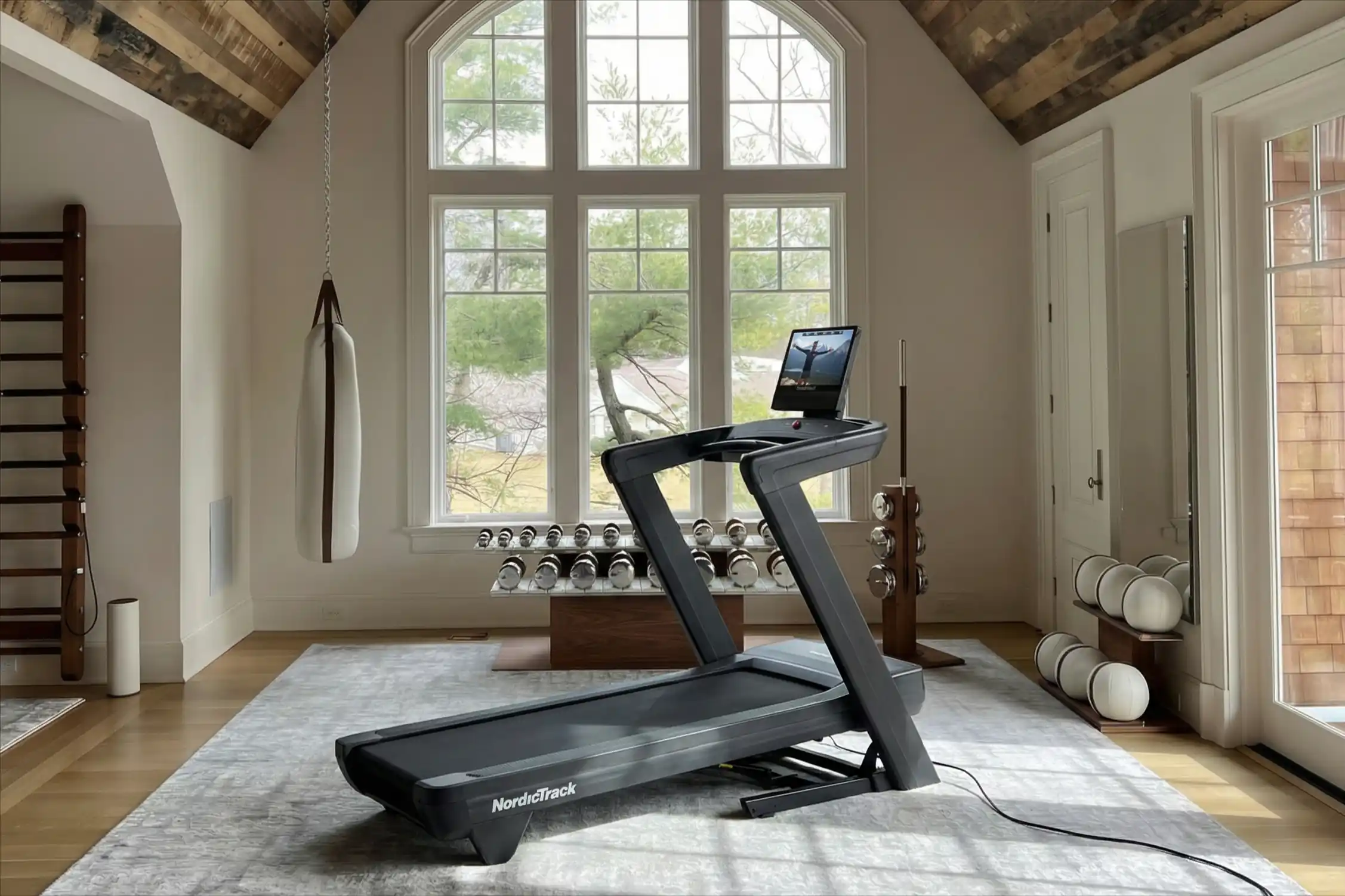 NordicTrack Commercial 1750 treadmill in an elegant home gym featuring arched windows, exposed ceiling beams, and modern workout equipment
