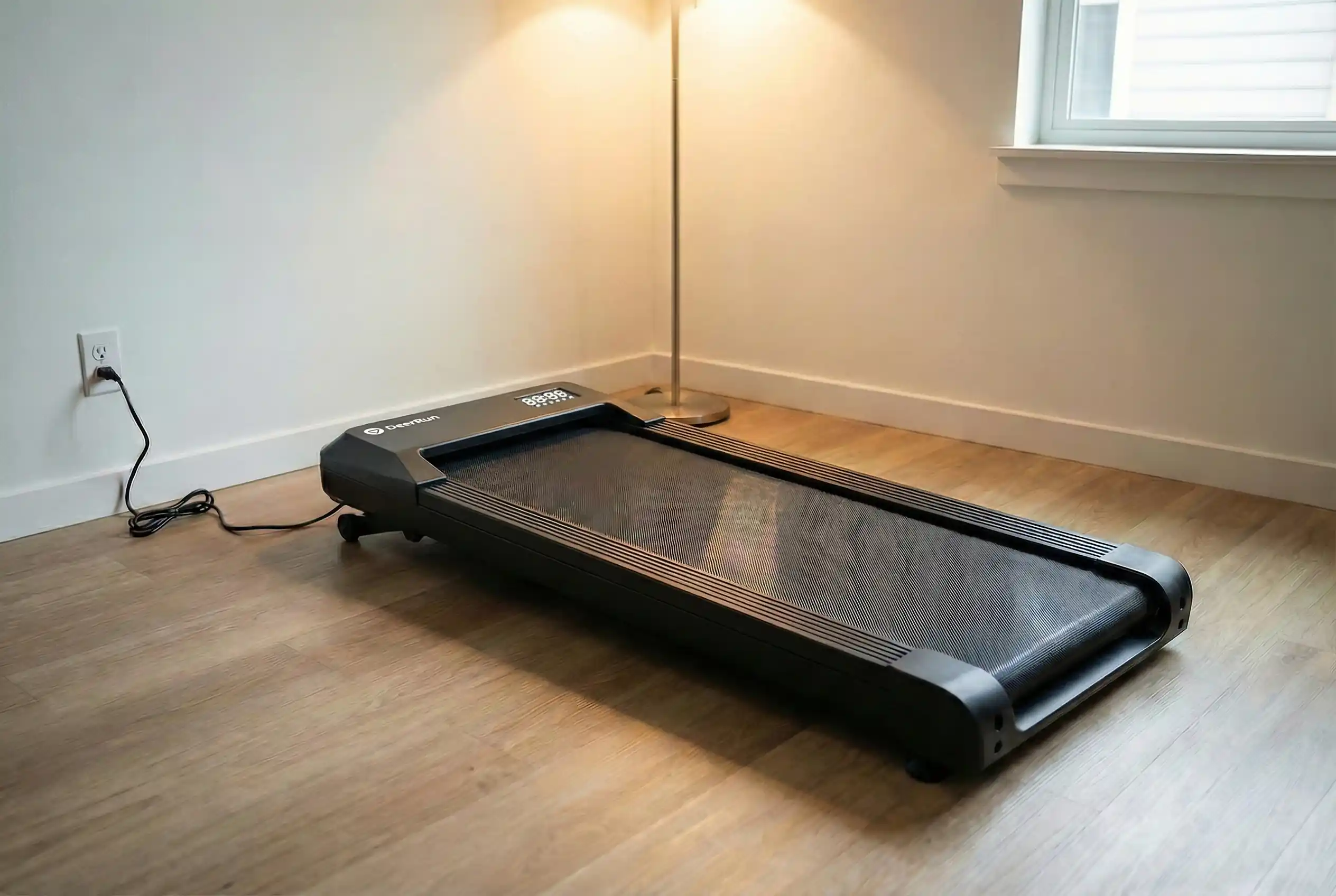 DeerRun Walking Pad compact treadmill with LED display panel on hardwood floor in corner with modern floor lamp and white walls