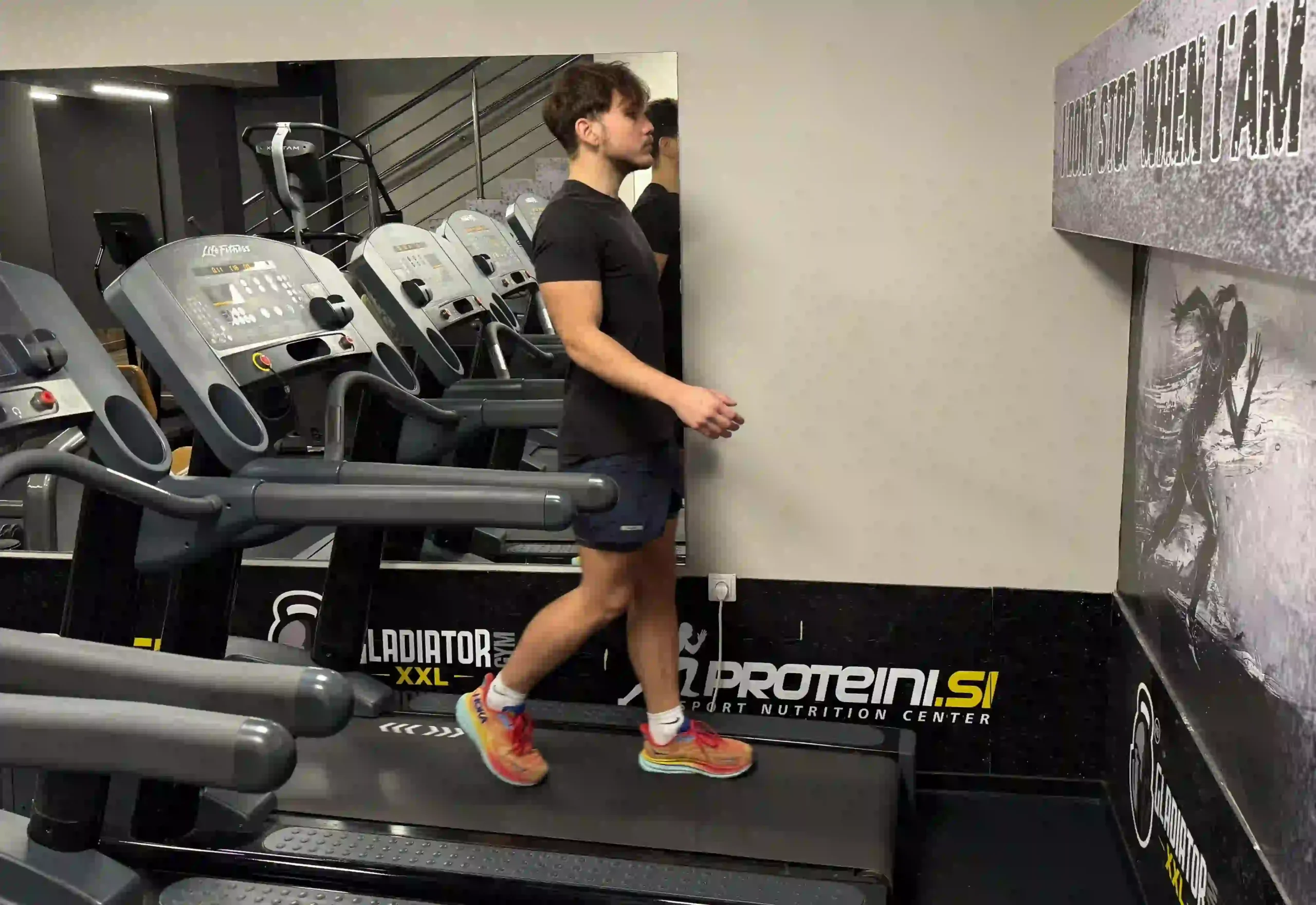 Milutin demonstrating proper technique for walking backwards on a treadmill, maintaining an upright posture without holding the handrails.