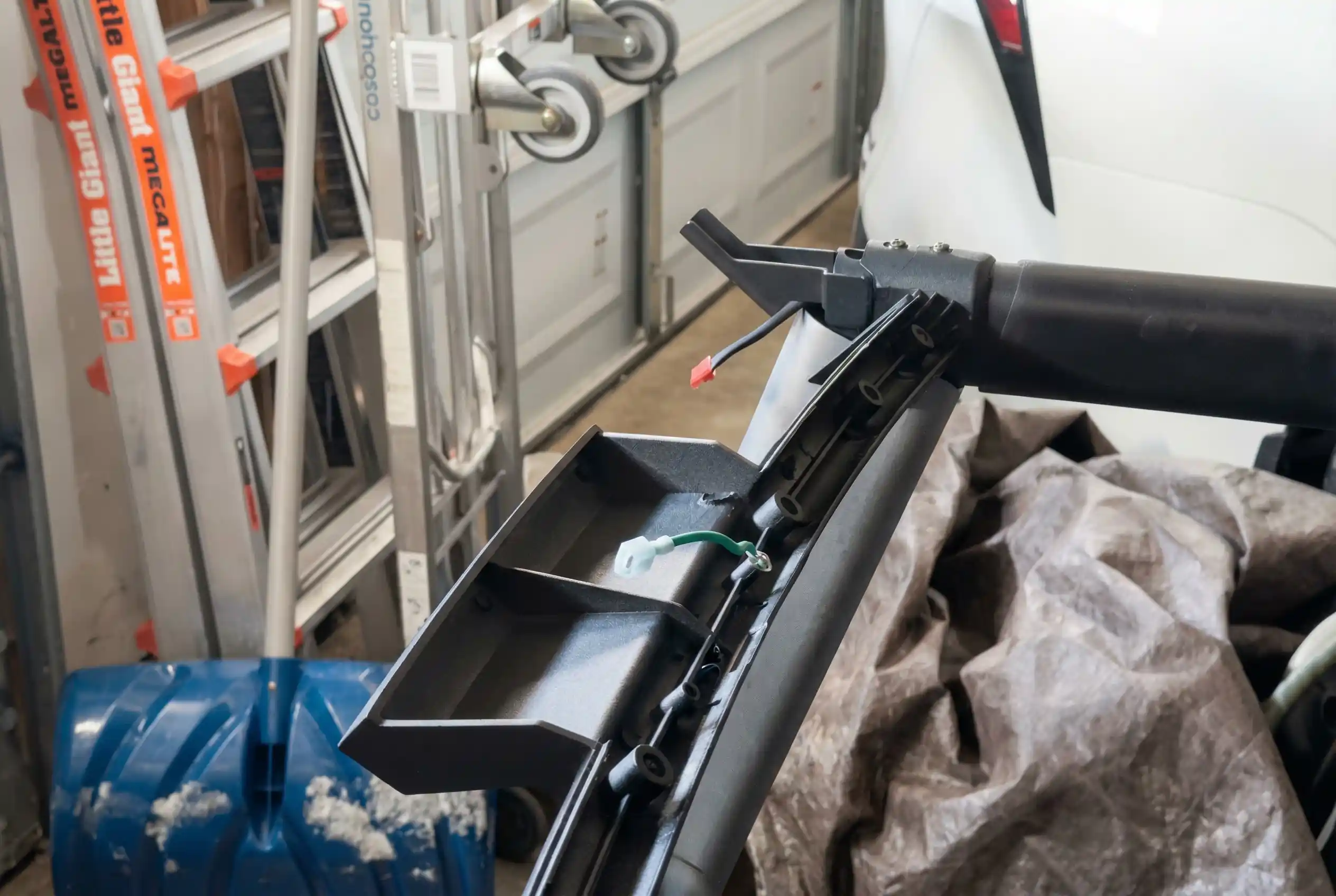 Treadmill console connector cable detached and lying in black frame channel with pink connector end visible and green connector clip, shown during disassembly in garage workshop setting