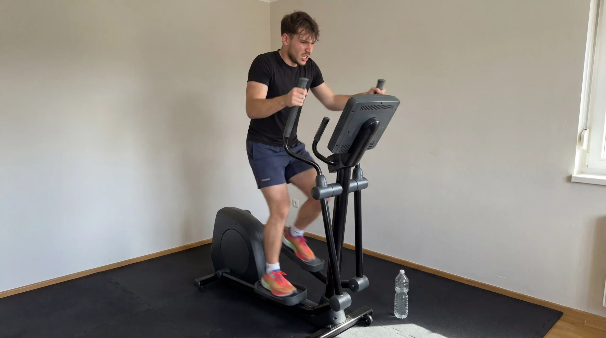 Milutin using an elliptical machine for an intense HIIT workout in a home gym environment.