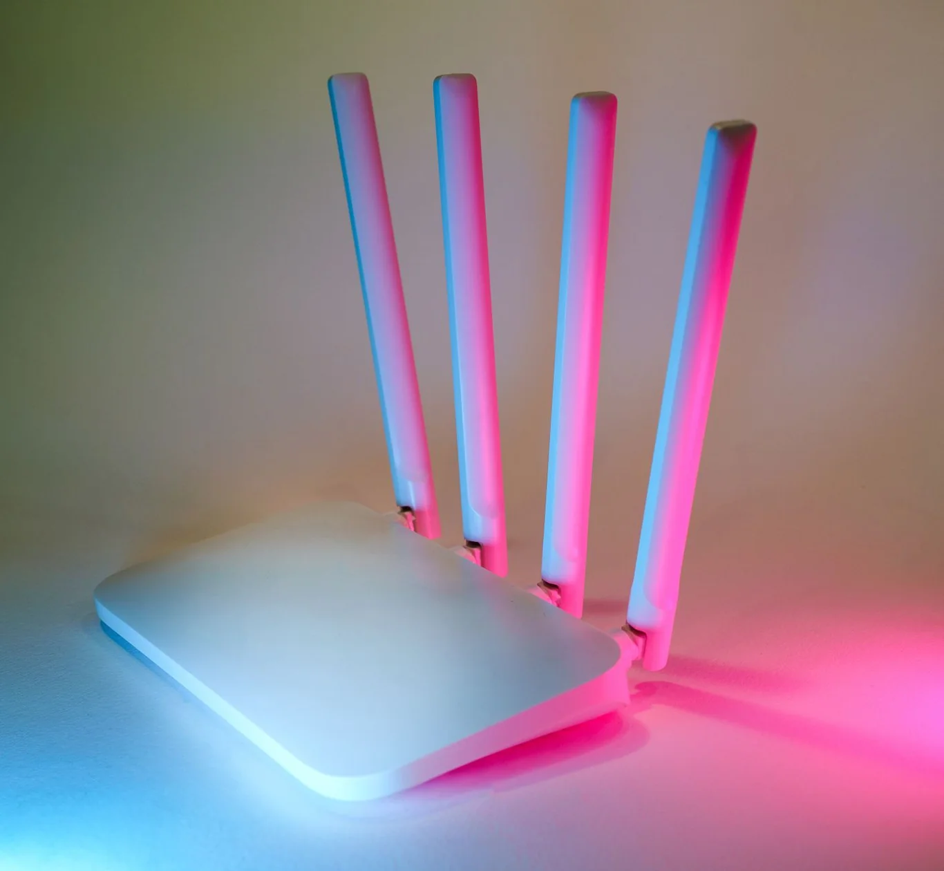 White Wi-Fi router with four antennas lit in blue and pink glow on a neutral background