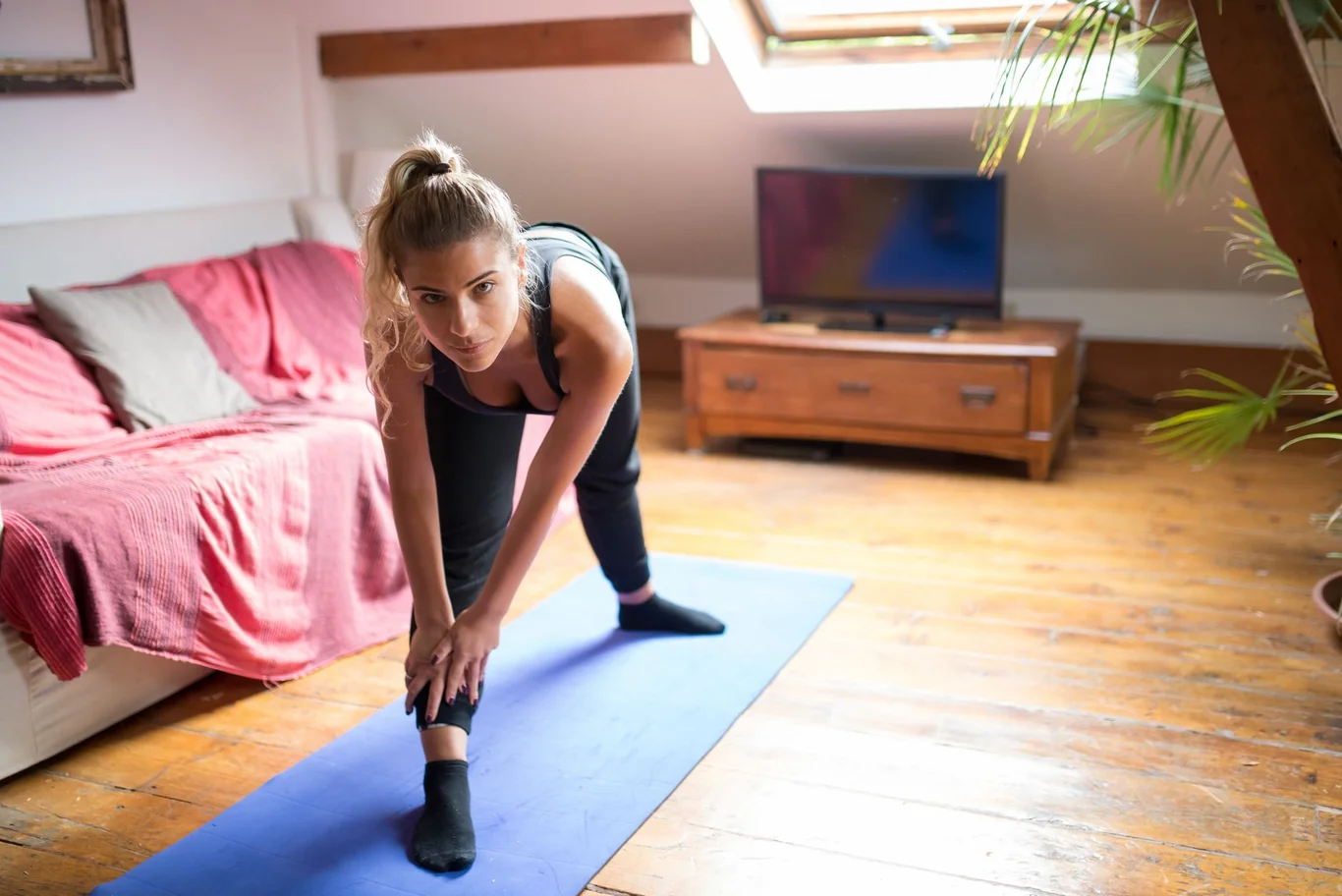 Woman stretching on a yoga mat in a home living room during a workout