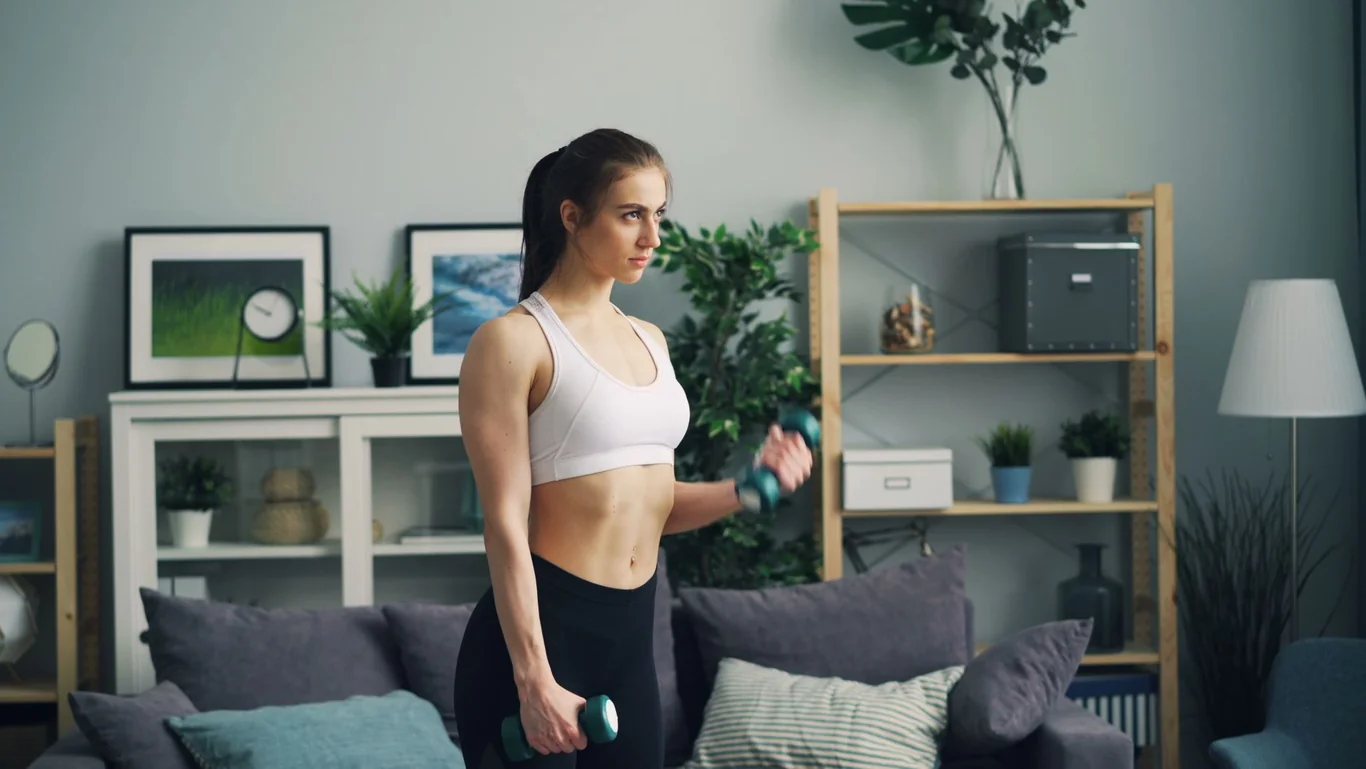 Woman doing dumbbell curls during a home workout in a modern living room