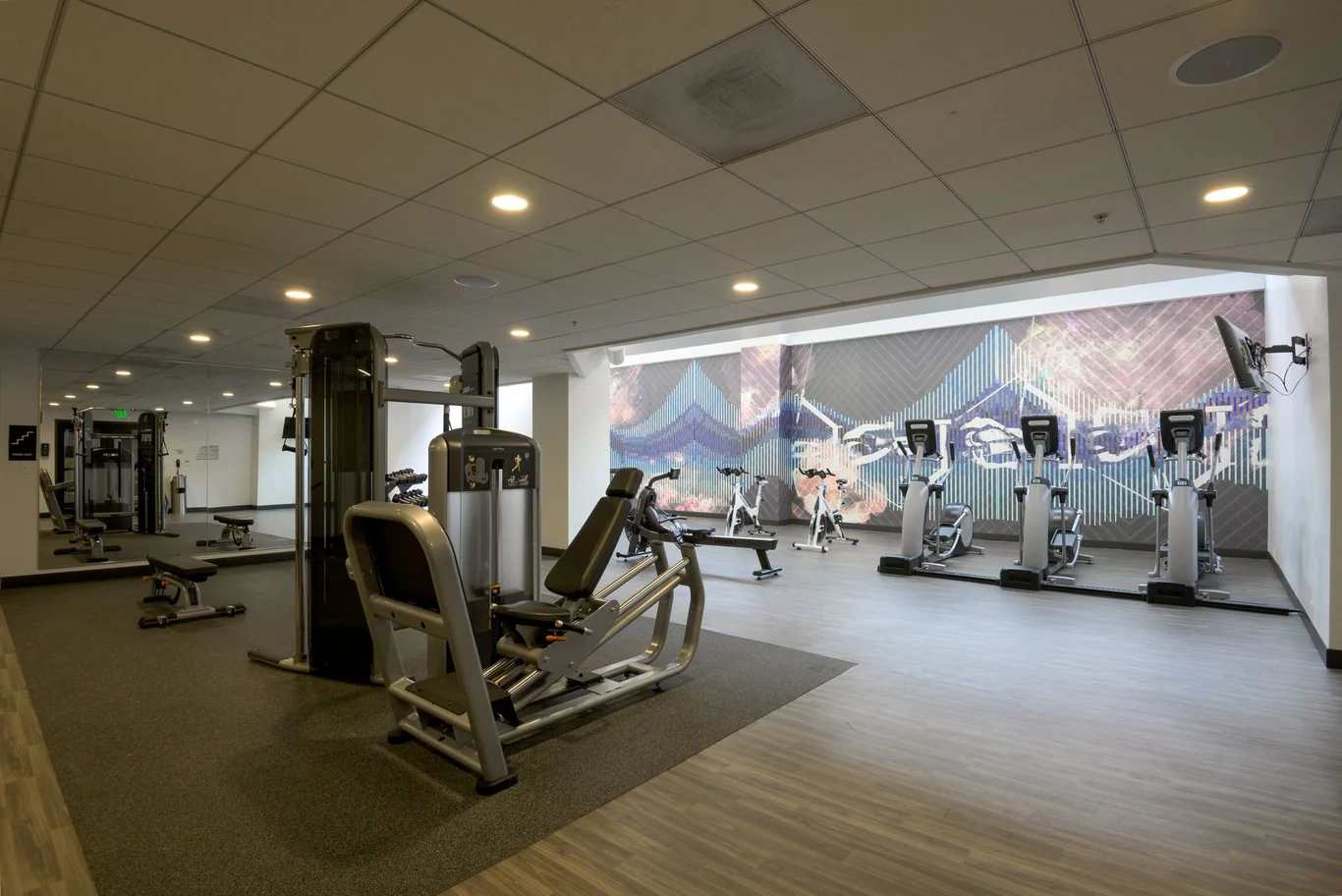 Spacious gym interior with cable machines and cardio equipment on hardwood floors