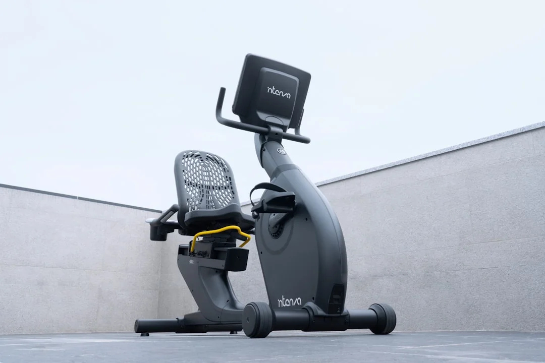 Recumbent exercise bike with mesh seat and touchscreen console on a light background