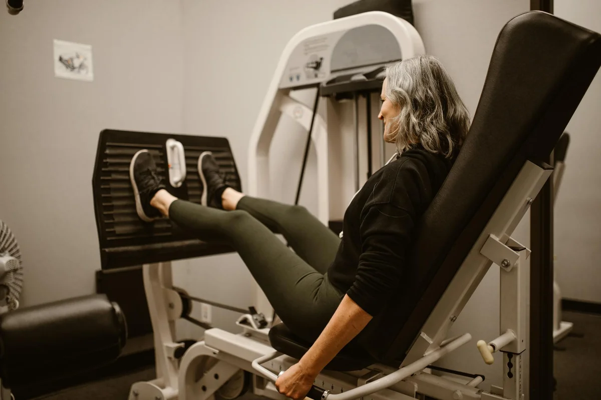 Woman on a leg press machine in a gym with legs fully extended in a reclined seated position