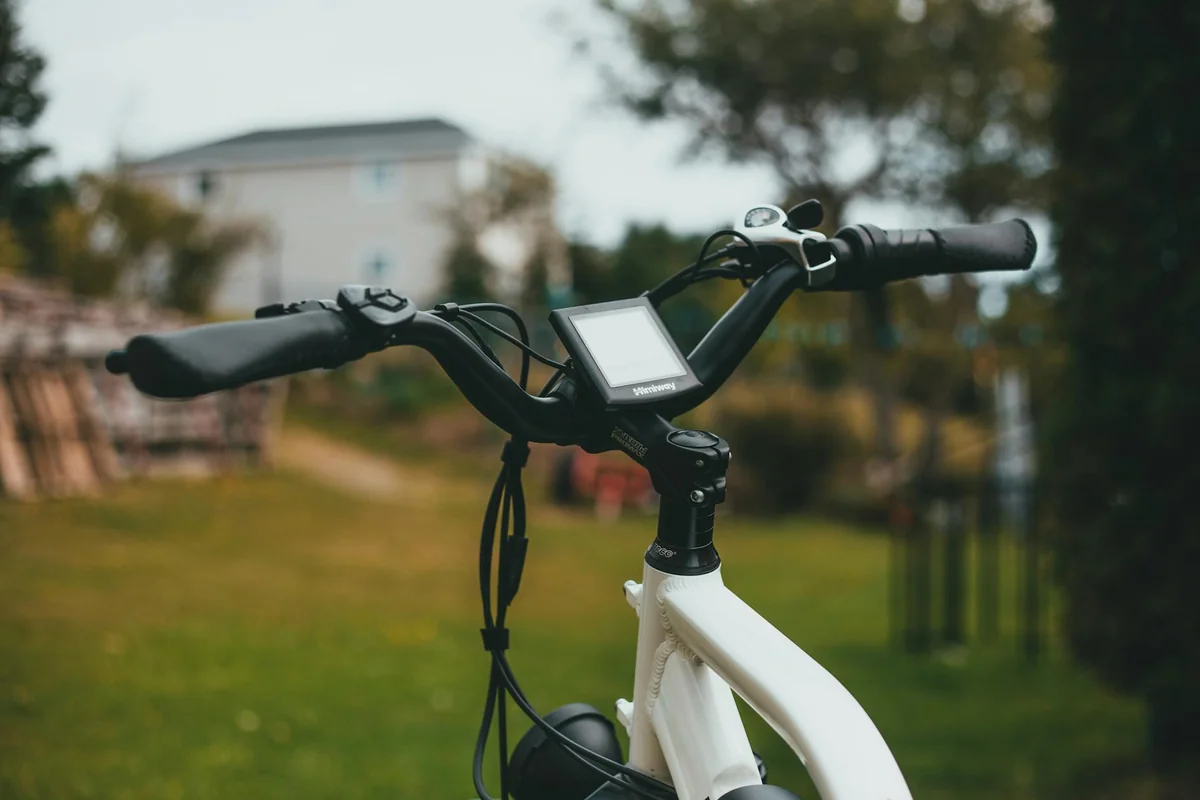 White bike handlebars with a compact digital display console mounted at the stem outdoors