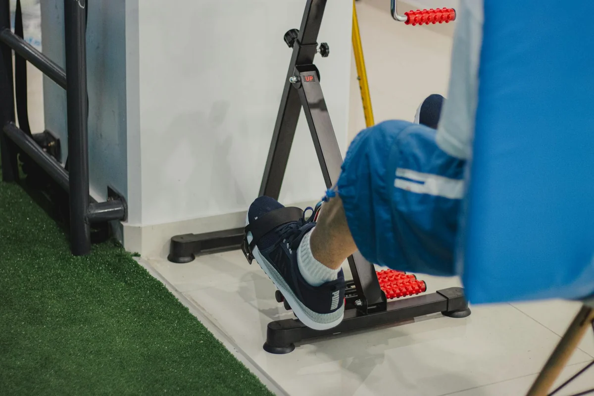 Person using a compact pedal exerciser machine indoors showing foot and lower leg position during cycling