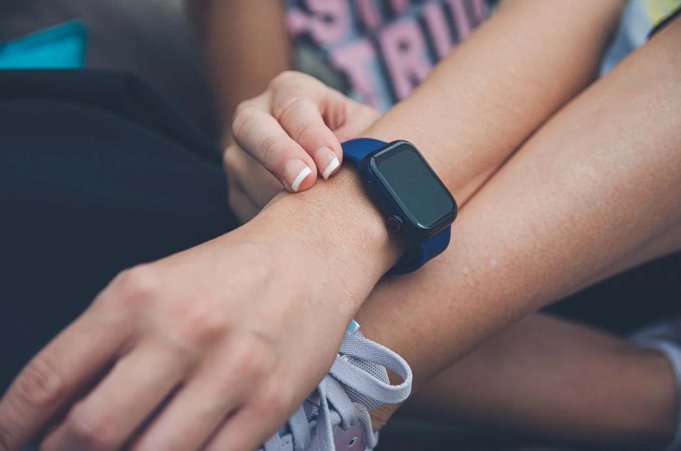Close-up of a hand adjusting a navy blue fitness tracker strap on the wrist