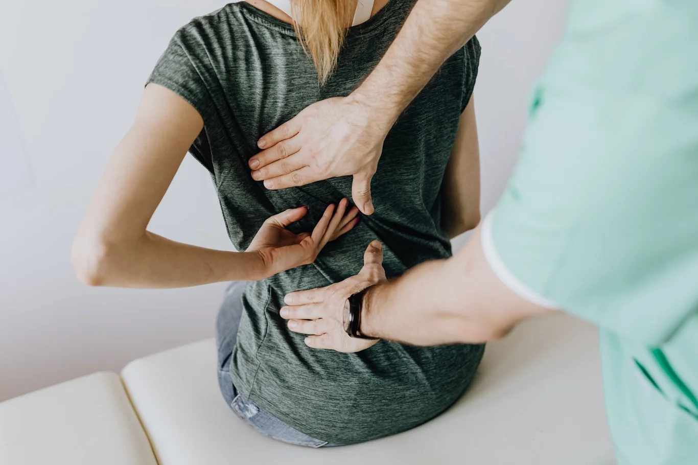 Physical therapist pressing both hands into a seated patient's lower back