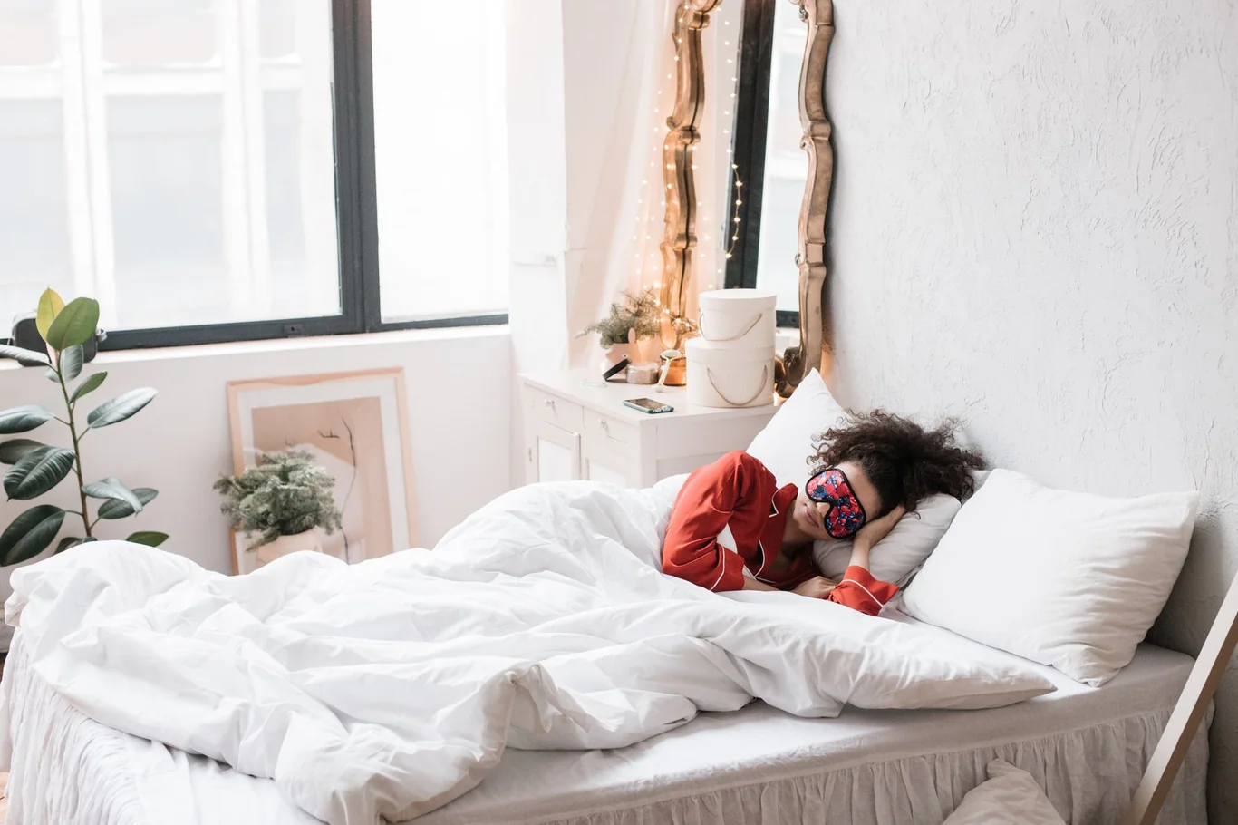 Woman sleeping in a bed wearing a red sleep mask and matching pajama top