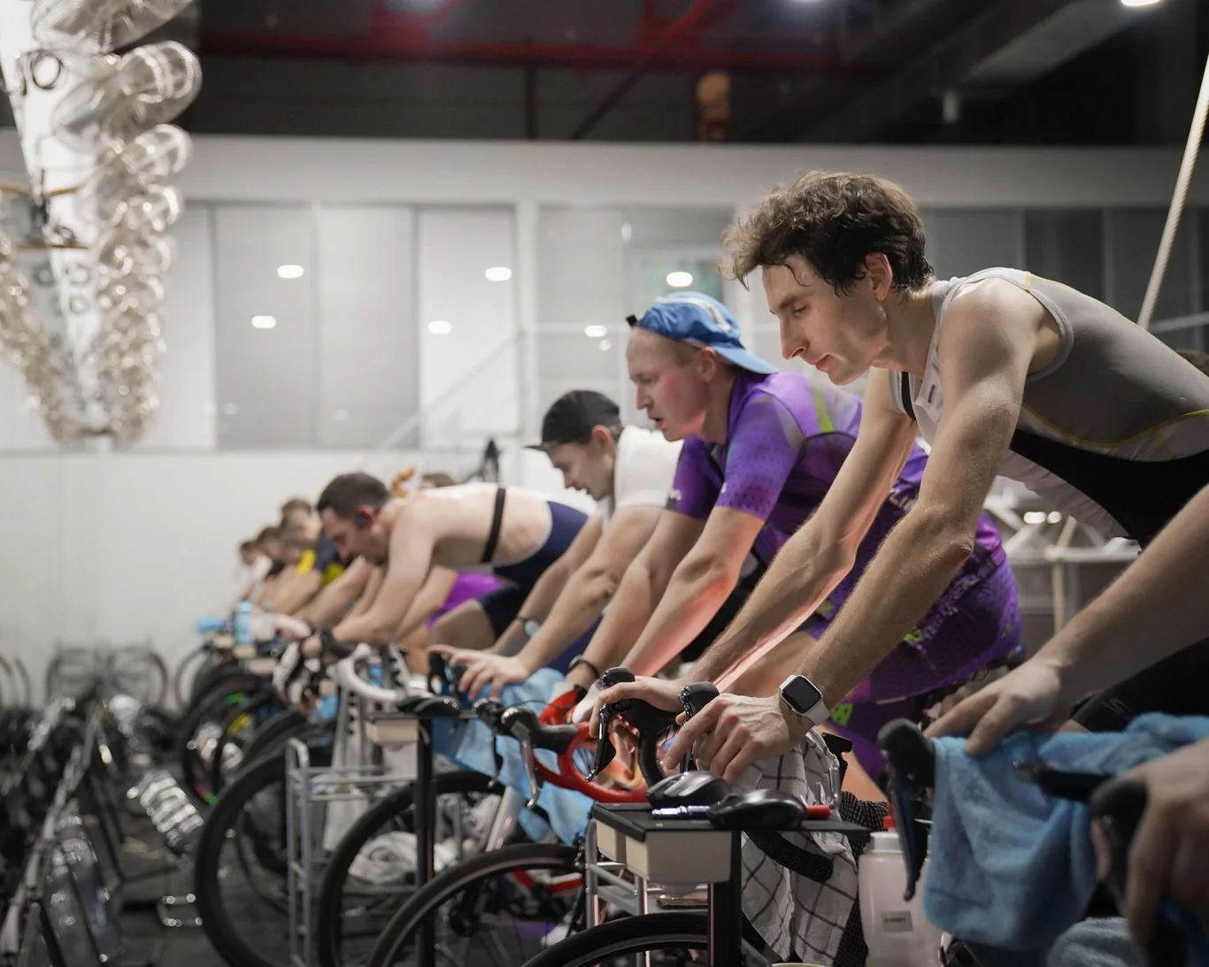 Cyclists pedaling stationary bikes in a row during an indoor spin class