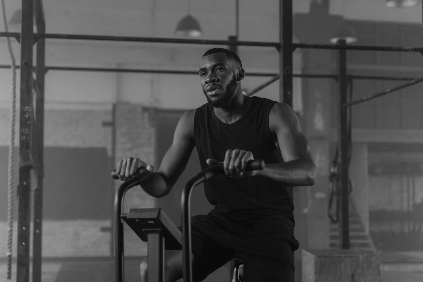 Man gripping the handlebars of an air exercise bike during a workout