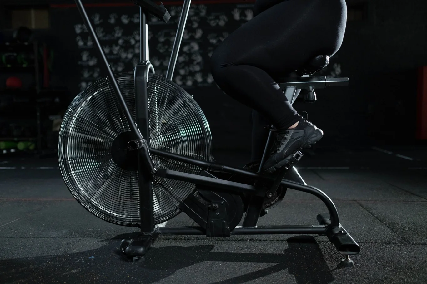 Stationary air bike with a large fan wheel, sturdy metal frame, and pedals