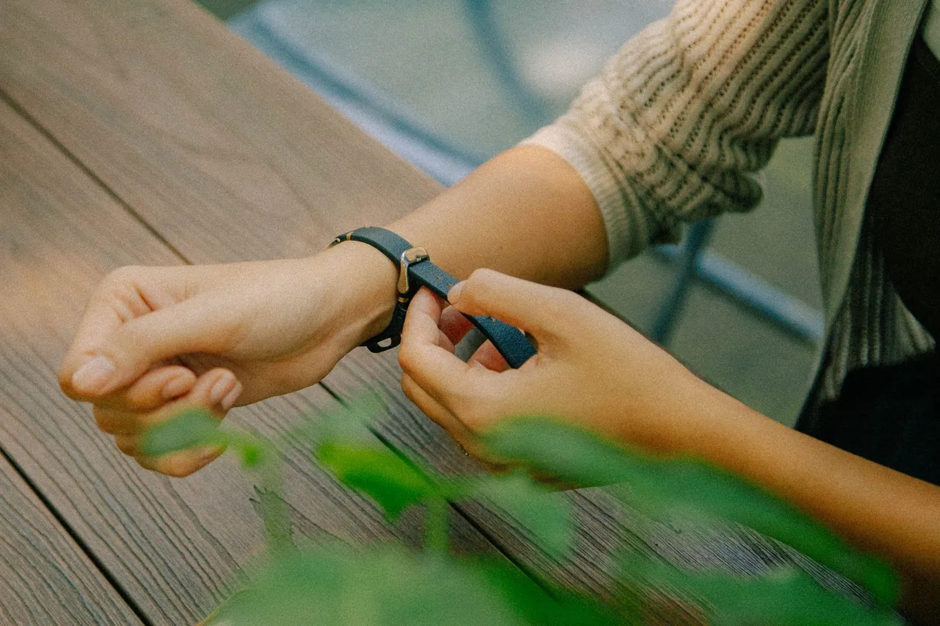 Person adjusting a smartwatch strap buckle on their wrist outdoors