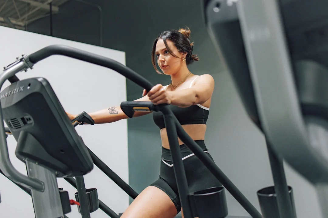 Woman working out on an elliptical machine in a gym setting