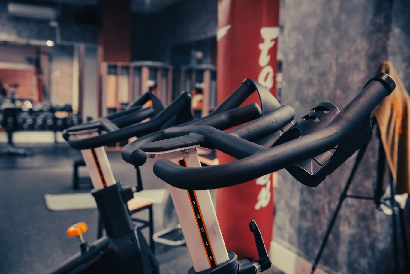 Close-up of spin bike handlebars and adjustable seat posts lined up in a gym