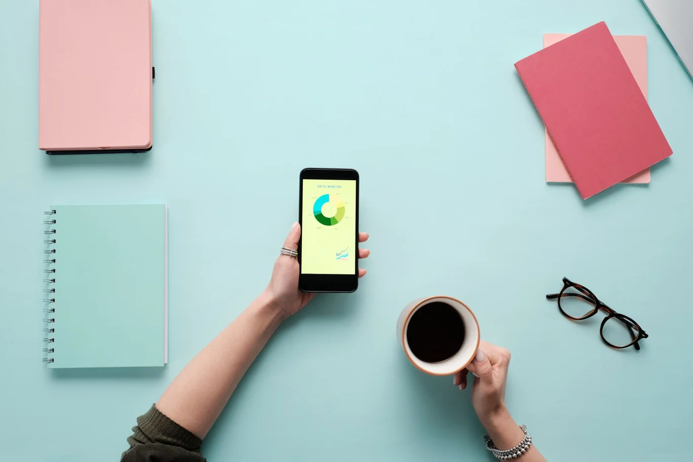 Hand holding a smartphone with a colorful chart on screen beside a coffee cup