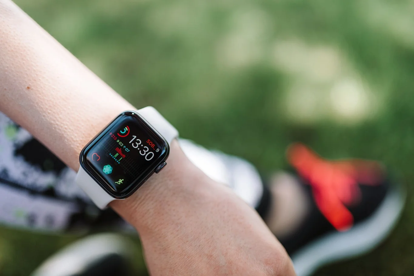 Smartwatch on a runner's wrist showing time and workout stats with a shoe blurred behind