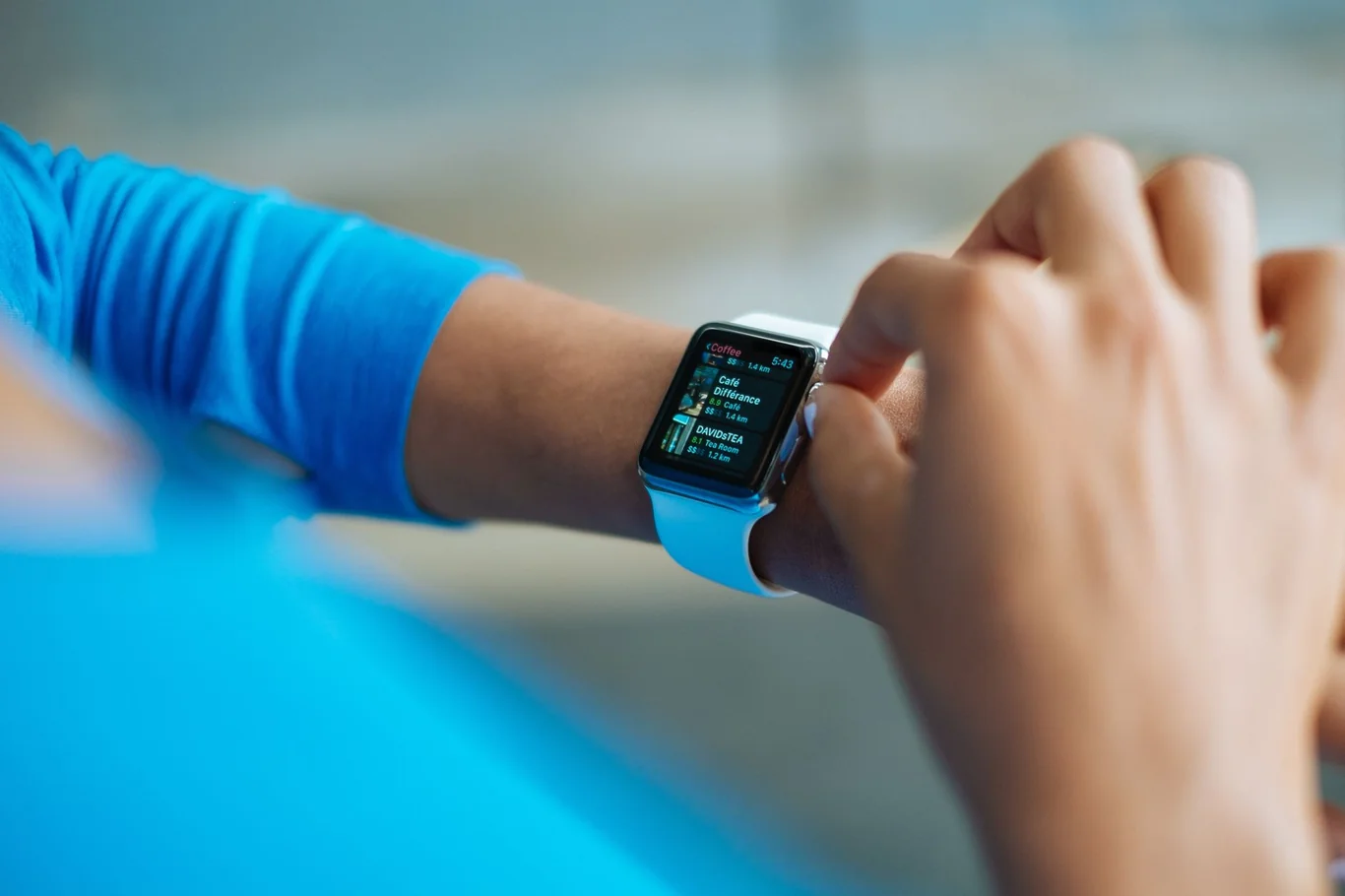 Person in a blue long sleeve top checking notifications on an Apple Watch