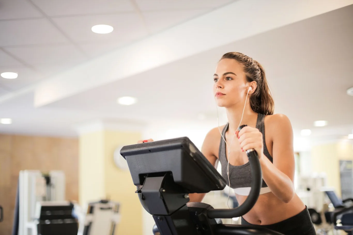 Woman gripping elliptical machine arm handles during a gym workout
