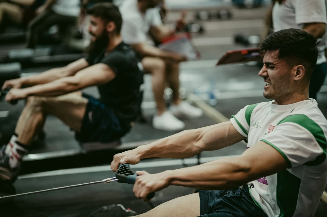 Athlete pulling hard on an indoor rowing machine during an intense workout