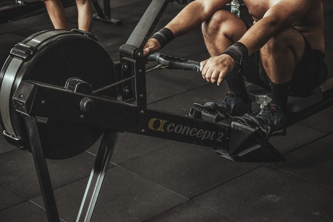 Person gripping a rowing machine handle with feet strapped into footrests