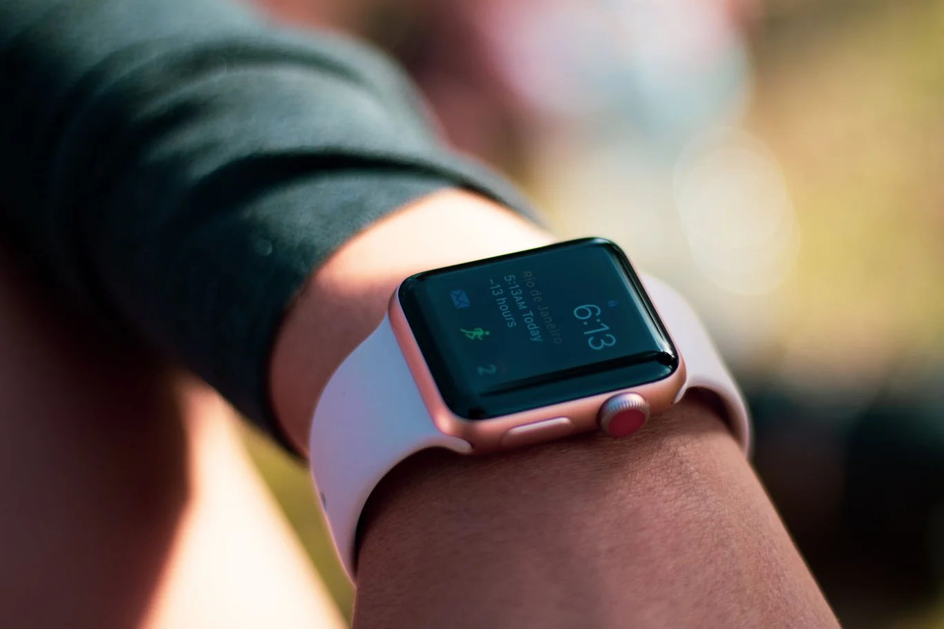 Person checking the time on a rose gold smartwatch worn on their wrist