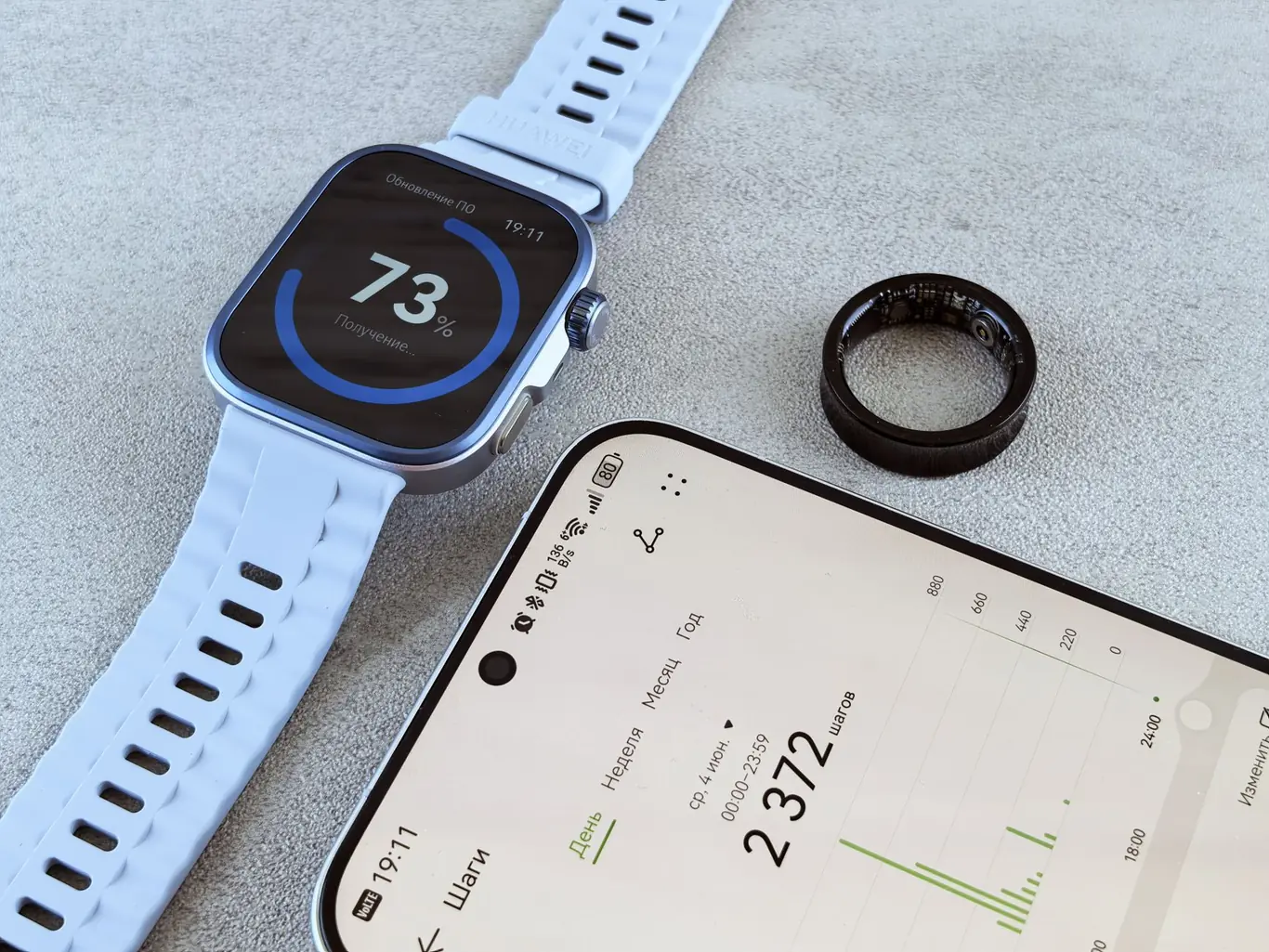 Smartwatch showing 73 percent battery next to a smartphone and a black ring