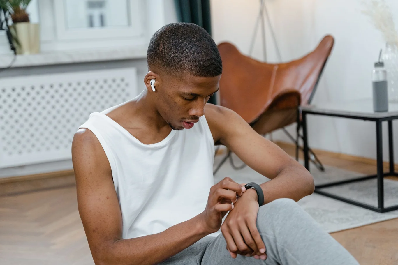 Man sitting on the floor at home checking a smartwatch on his wrist