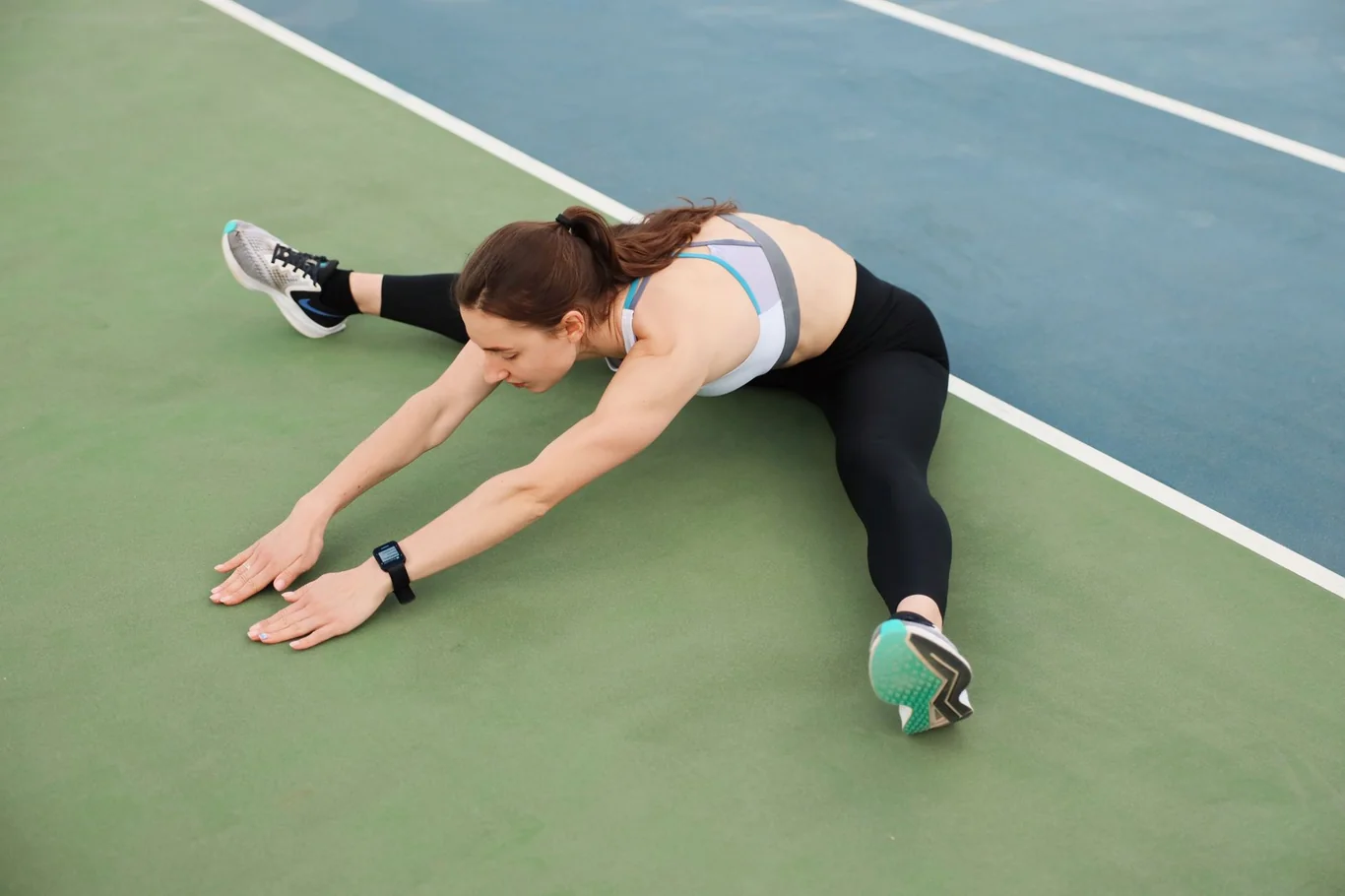 Woman stretching on a sports court while wearing a fitness tracker on her wrist