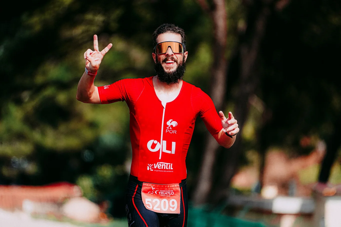 Man in red activewear celebrating with a peace sign at a race finish area