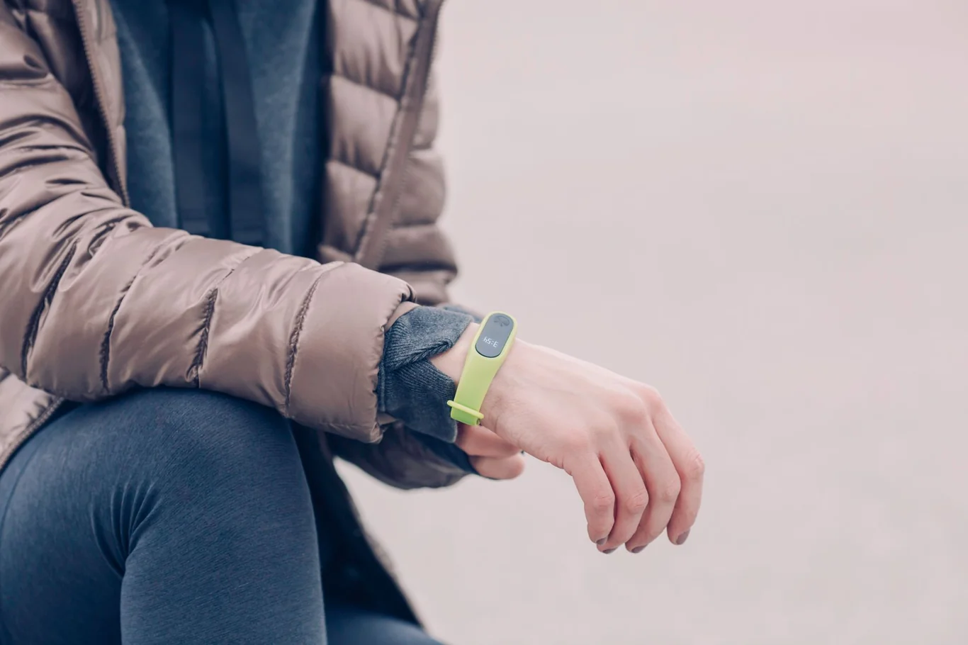 Fitness tracker band worn on the wrist with a hand checking the screen