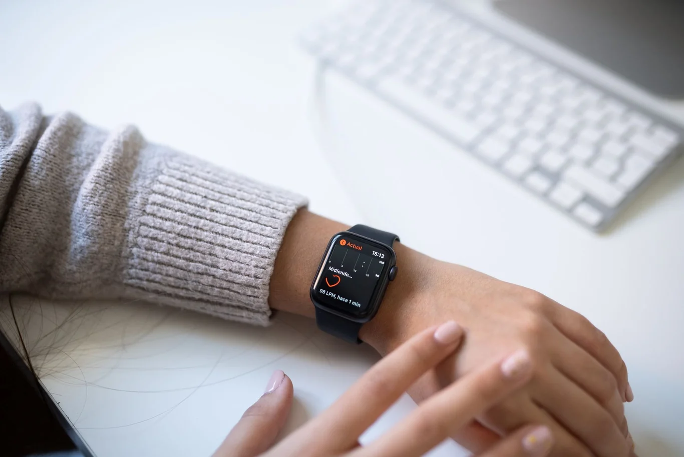 Fitness tracker on a wrist beside a keyboard showing an active workout