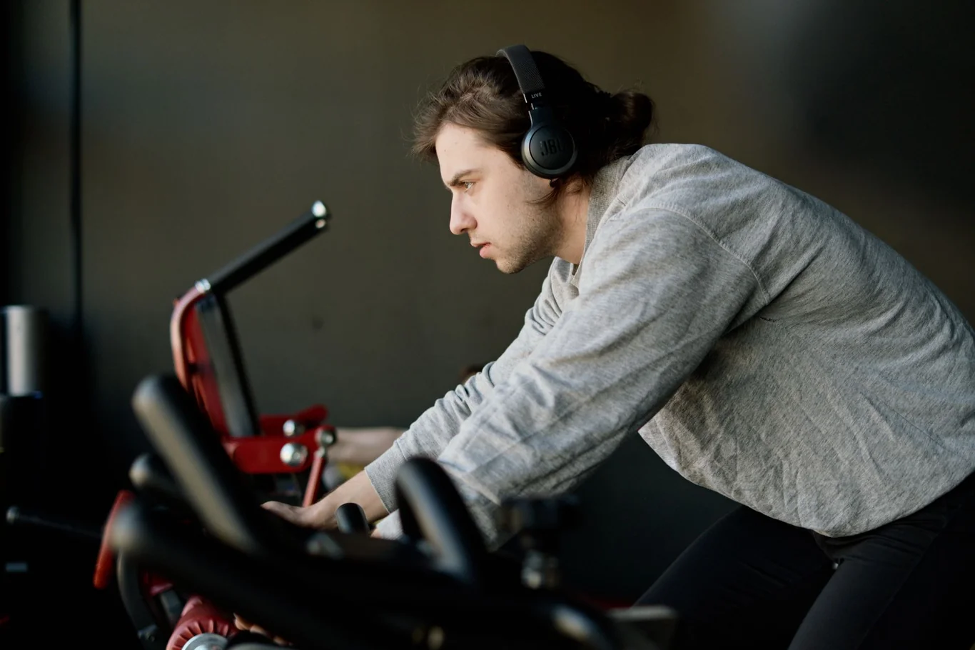Man wearing headphones riding a red indoor exercise bike in a home gym