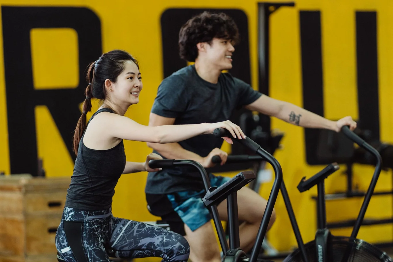 Man and woman using stationary exercise bikes together in a gym