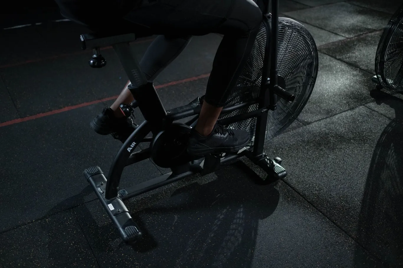 Close-up of a cyclist's legs pedaling a stationary exercise bike indoors