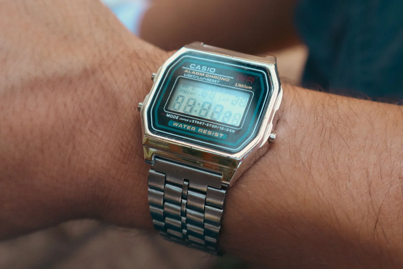 Digital watch with metal band displaying the time on a person's wrist