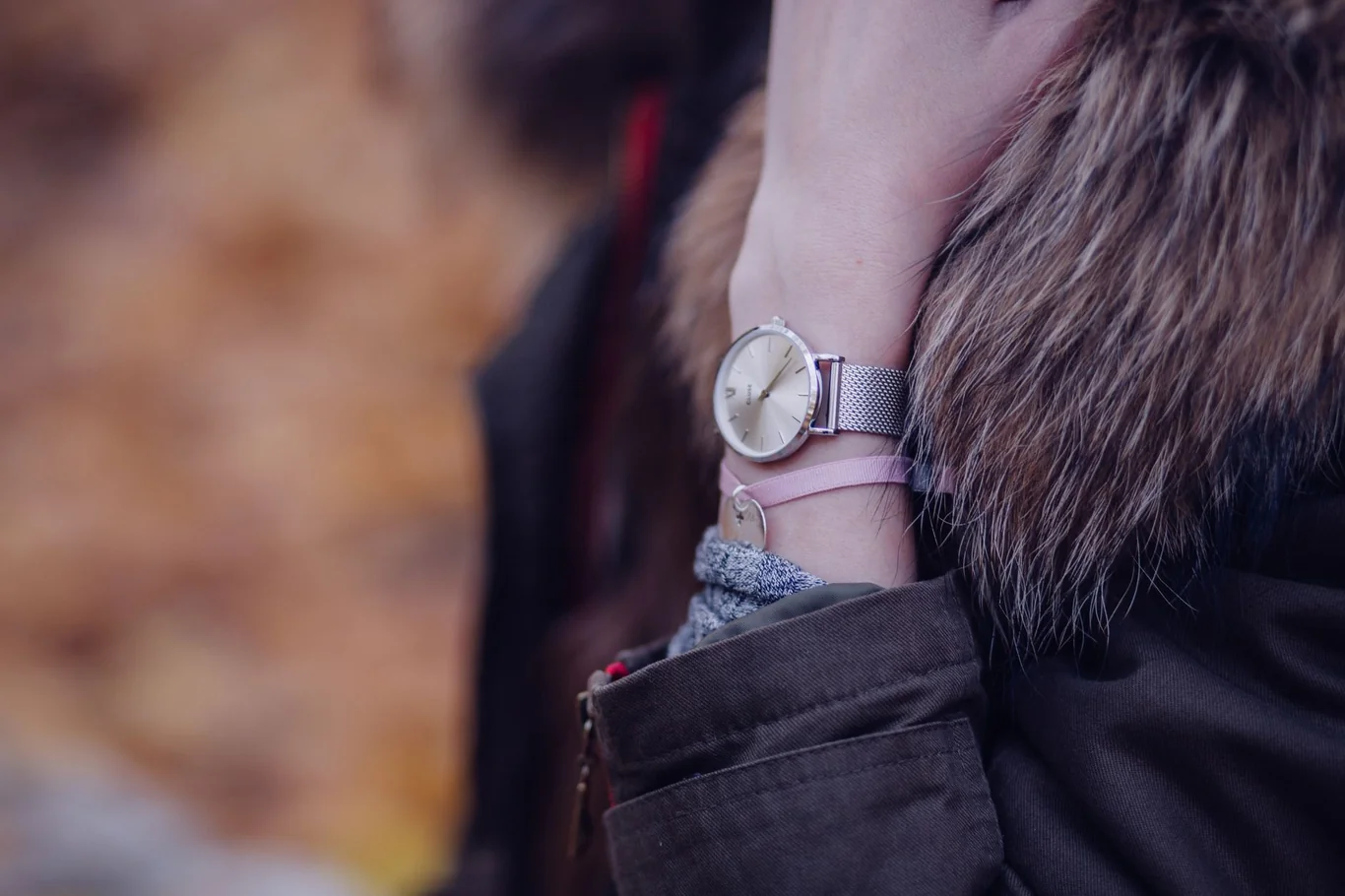 Person wearing a simple analog watch while outdoors in autumn