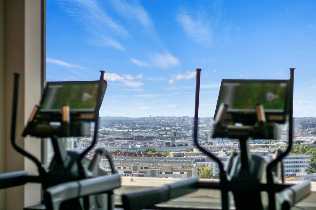 Two elliptical machines on a rooftop gym overlooking a city skyline