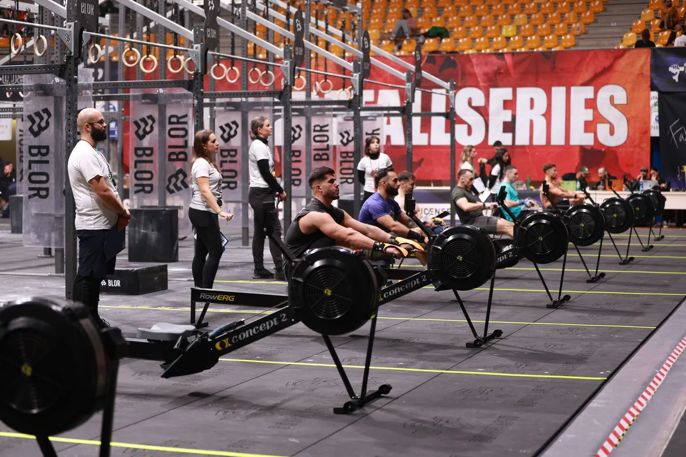 People training side by side on Concept2 RowErg machines at an indoor rowing event