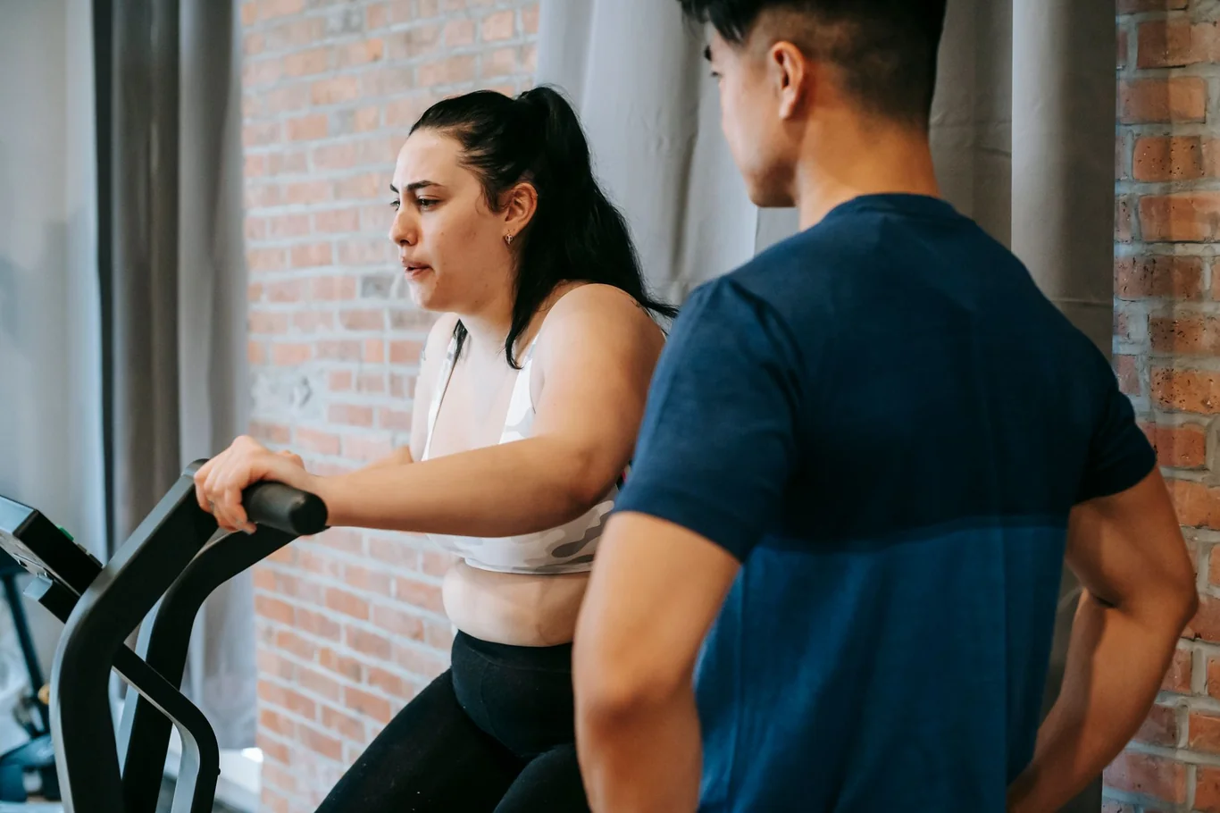 Woman gripping the moving handles of an elliptical machine during a gym workout