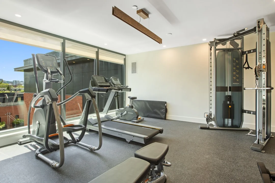 Elliptical machine in a modern home gym with floor-to-ceiling windows and a cable station