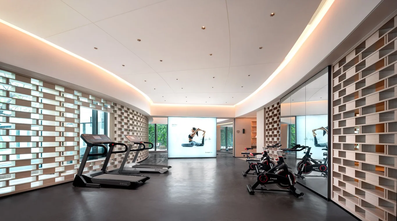 Modern fitness room with two treadmills, stationary bikes, and mirrored walls