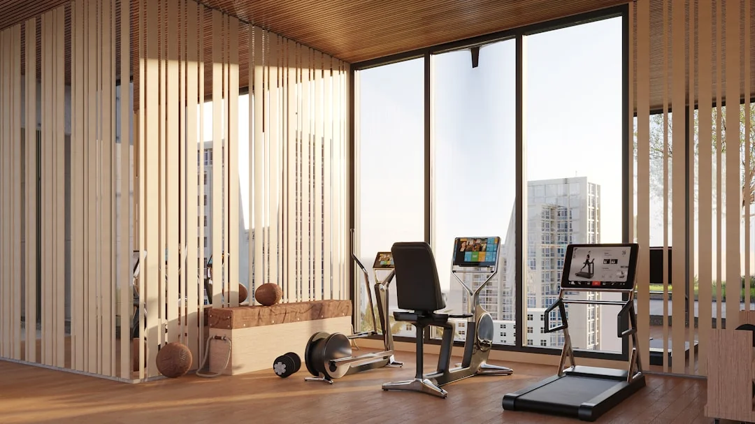 Modern gym room with wood slat walls, a treadmill, elliptical, and dumbbells near a window