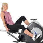 Stamina Conversion II in recumbent bike configuration, woman seated with feet on the pedals near the flywheel, seat rail retracted