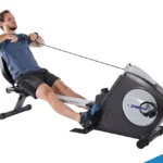 Stamina Conversion II in rower configuration, man seated pulling the rowing handle with the seat rail extended