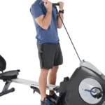 Stamina Conversion II in rower configuration, man standing beside the machine pulling the rowing handle for a standing upper body exercise