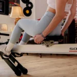 Close-up of a woman adjusting the Sole rower seat rail lock mechanism